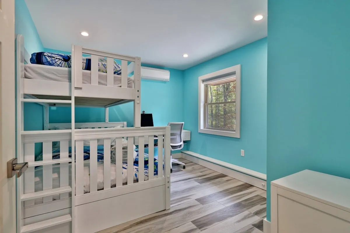 A cheerful bedroom space with a bunk bed and a desk and chair positioned near a window. The scene suggests a playful yet functional environment, with natural light spilling in and a welcoming vibe for both work and downtime.