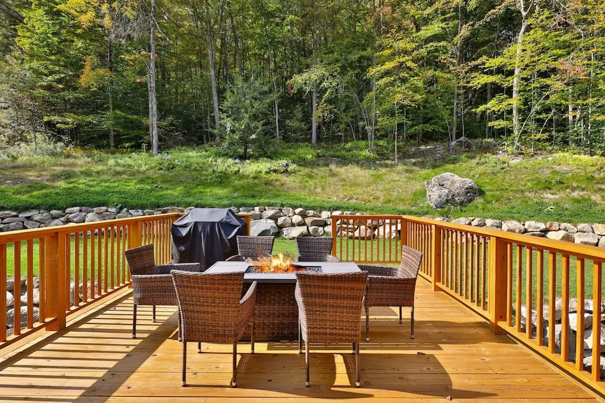 The photo shows an outdoor dining table with chairs and a fire pit set against lush greenery. The setup invites socializing, dining, and gathering around the fire for cozy evenings, echoing the fire pit and outdoor gathering themes described in the section.